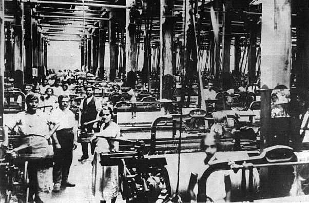 Operários ao lado das máquinas no interior de uma tecelagem paulistana, no início do séc. XX